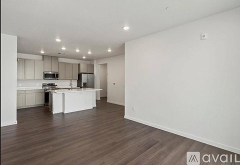 A spacious kitchen with white cabinets and a wooden floor.