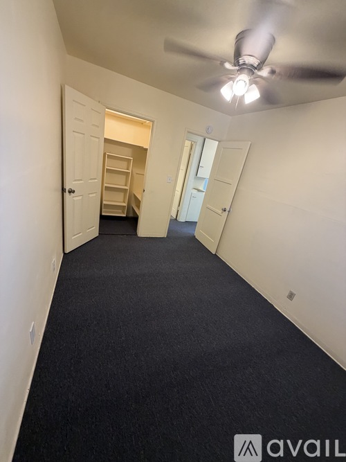 A long hallway with a carpeted floor and a ceiling fan.