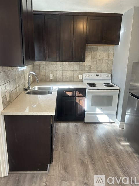 A kitchen with a white stove top oven and a sink with a silver faucet.