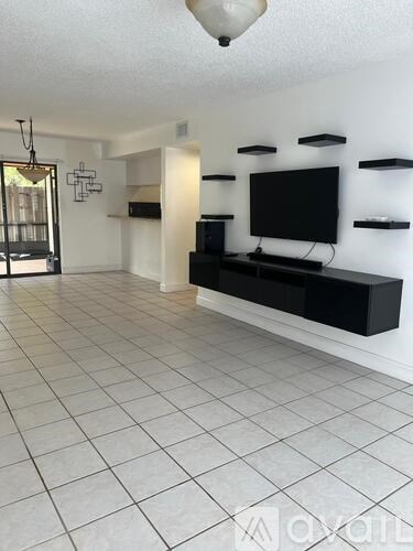 A black television is on a black stand in a white room.