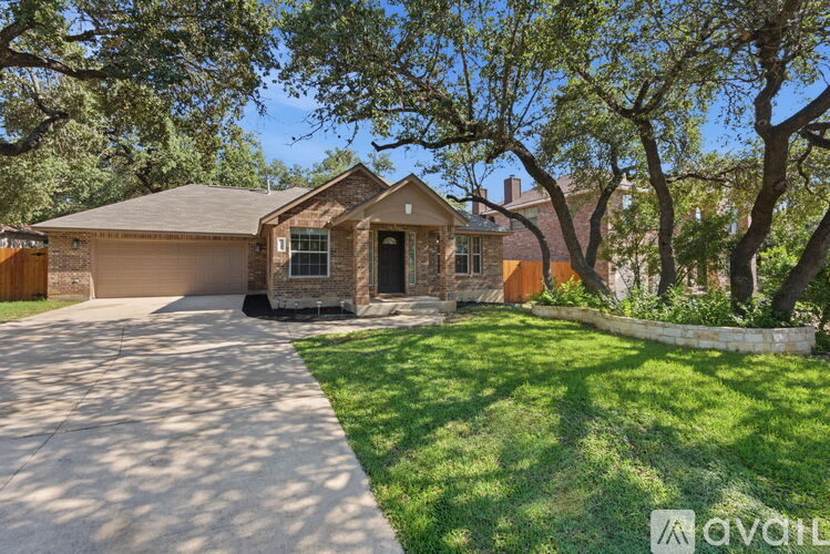 A house with a driveway and trees in front.