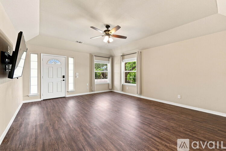 A spacious room with a ceiling fan and wooden flooring.