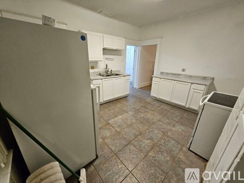 A kitchen with white cabinets and a tiled floor.