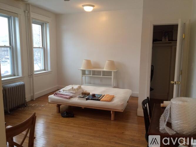 A bedroom with a bed, chair, and window.