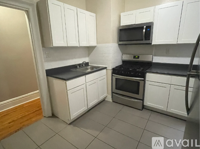 A kitchen with white cabinets and a black countertop.