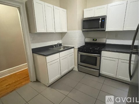 A kitchen with white cabinets and a black countertop.