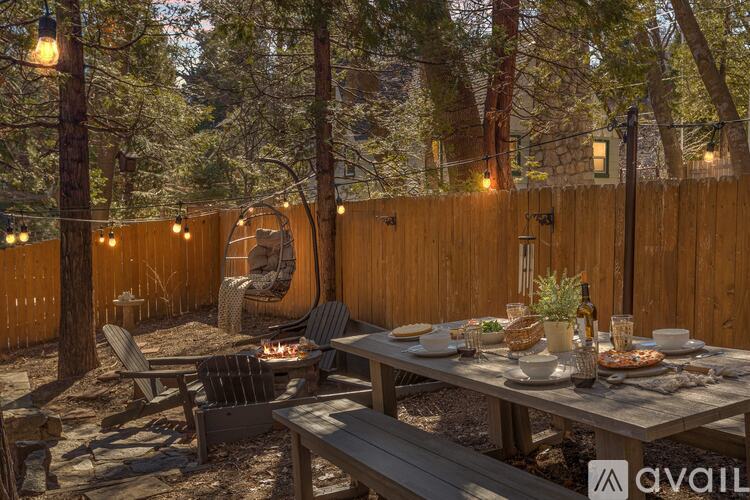 A backyard with a table set for a meal surrounded by trees.