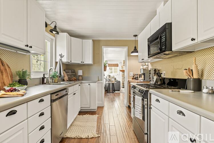 A kitchen with white cabinets and a wooden floor.