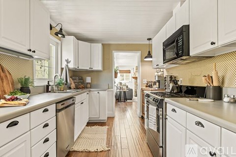 A kitchen with white cabinets and a wooden floor.