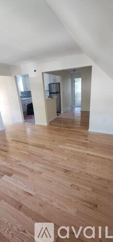 A spacious room with wooden flooring and white walls.