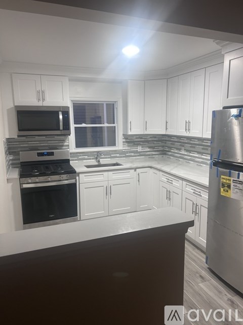 A kitchen with white cabinets and a stainless steel refrigerator.