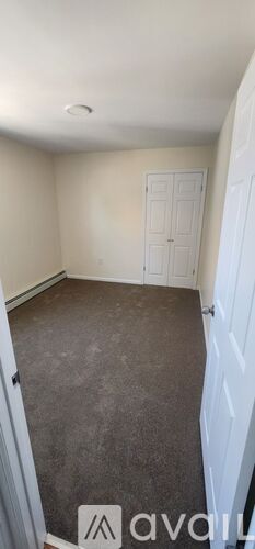 A room with a carpeted floor and a white door.
