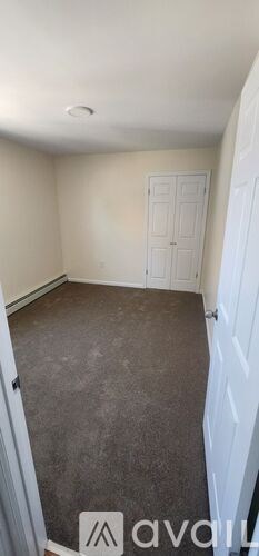 A room with a carpeted floor and a white door.