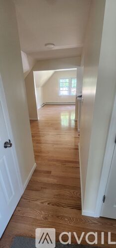A hallway with wooden floors and white walls.