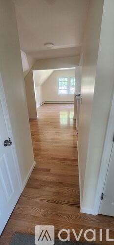 A hallway with wooden floors and white walls.