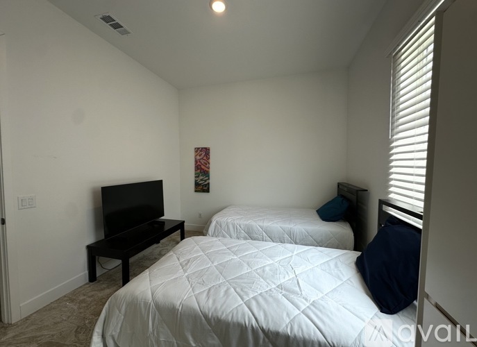 A bedroom with two beds and a television.