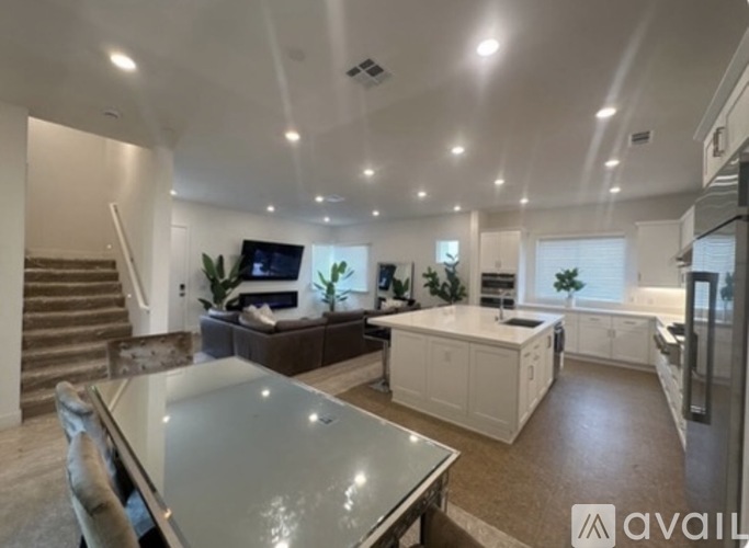 A modern kitchen with a glass table and a staircase in the background.