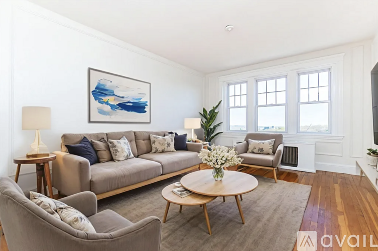 A living room with a grey couch, a brown coffee table, and a painting on the wall.