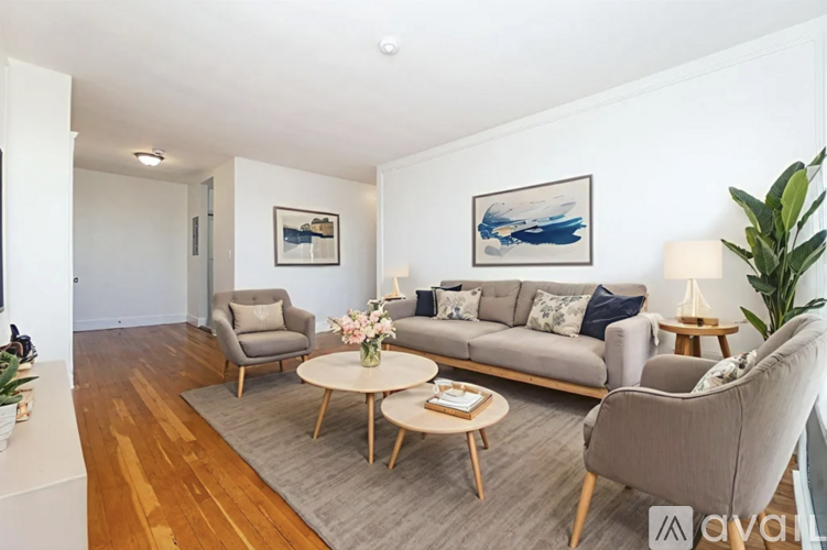 A living room with a grey couch, a wooden coffee table, and a painting on the wall.