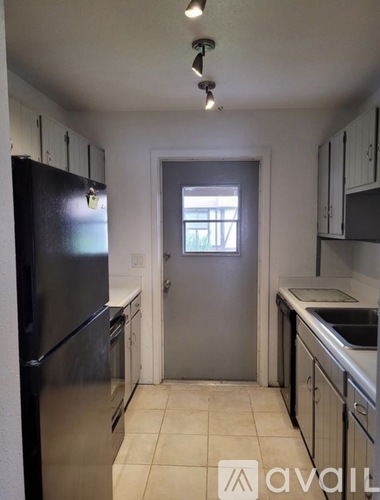 A kitchen with a black fridge, stainless steel dishwasher and a window.