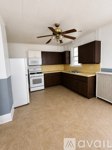 A kitchen with a white refrigerator, brown cabinets, and a ceiling fan.