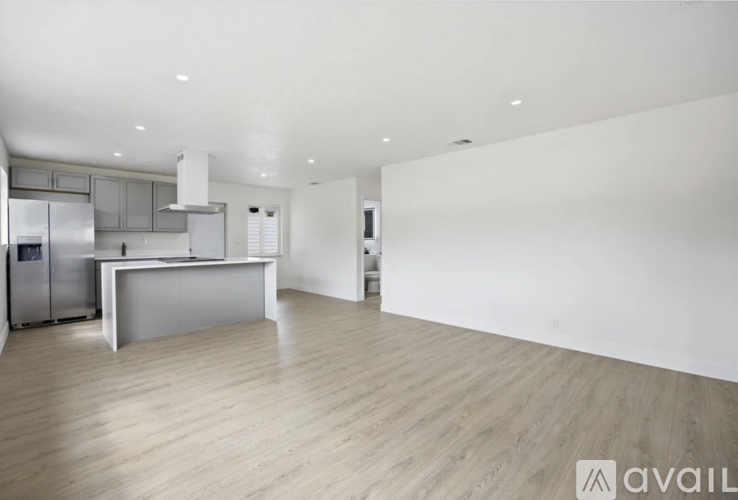 A modern kitchen with wooden flooring and white walls.