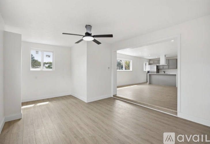 A spacious room with a ceiling fan and light wood flooring.
