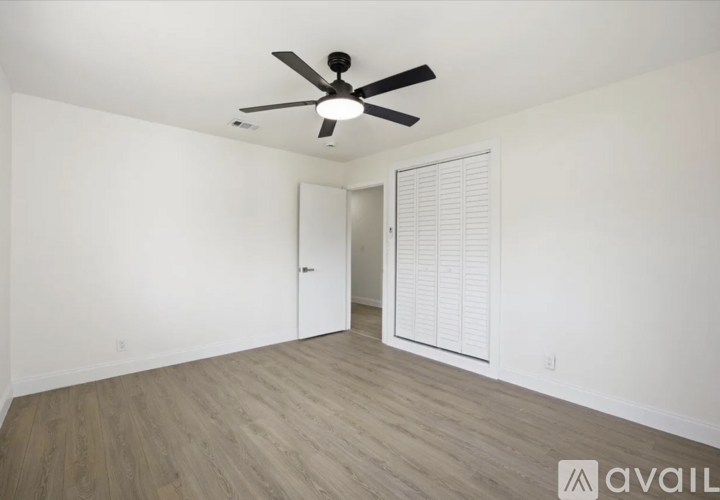 A room with a ceiling fan and a door with blinds.