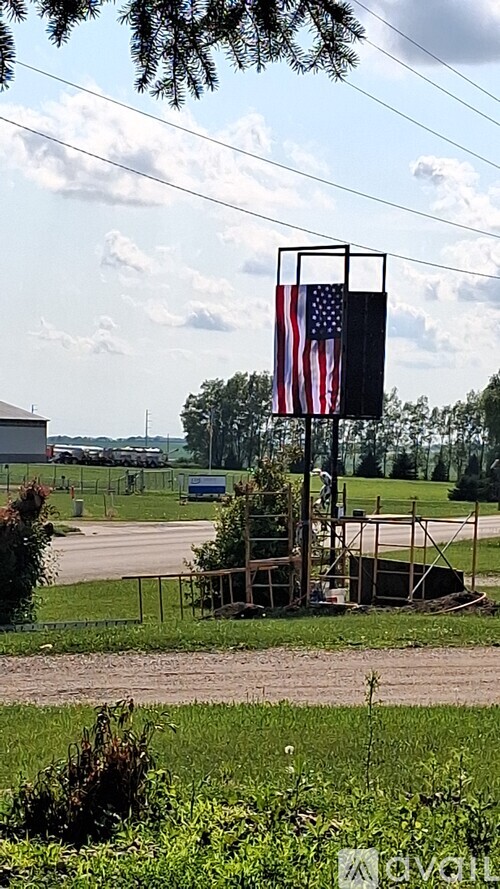 A flag on a pole with a metal frame is displayed in a field.