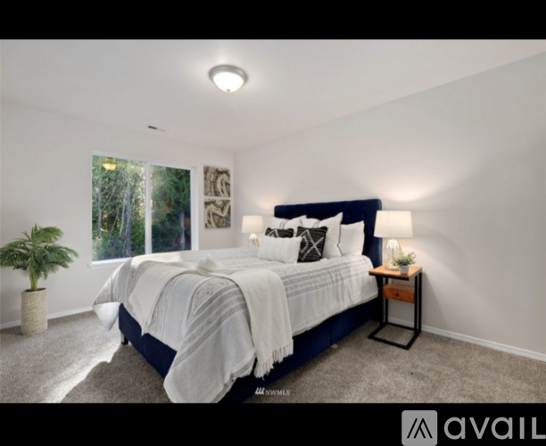A bedroom with a large bed and a potted plant.