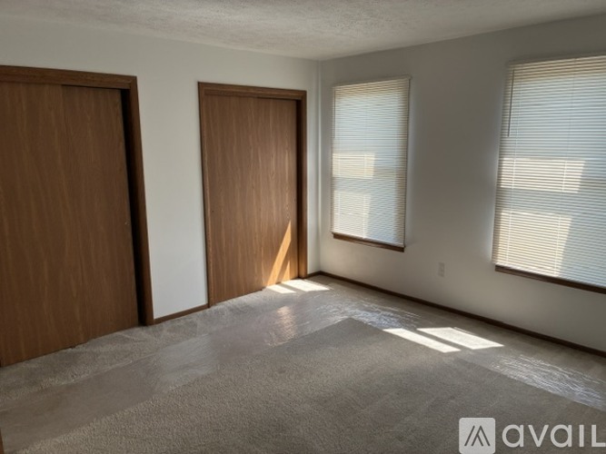 A room with two doors and a window with blinds.