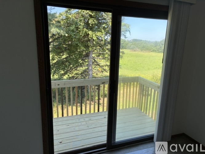 A balcony with a view of a green field and trees.