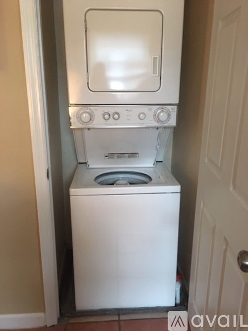 A white front loading washing machine in a narrow space.