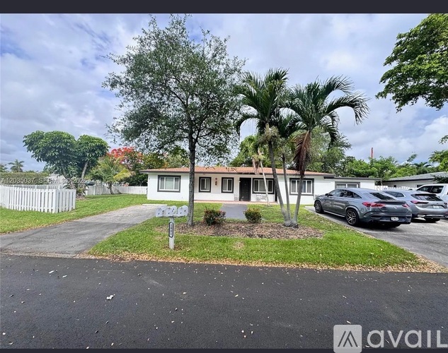 A house with a white fence and a tree in front of it.