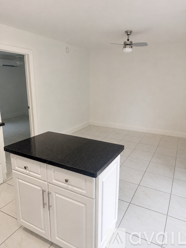 A kitchen with white cabinets and a black countertop.