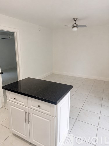 A kitchen with white cabinets and a black countertop.