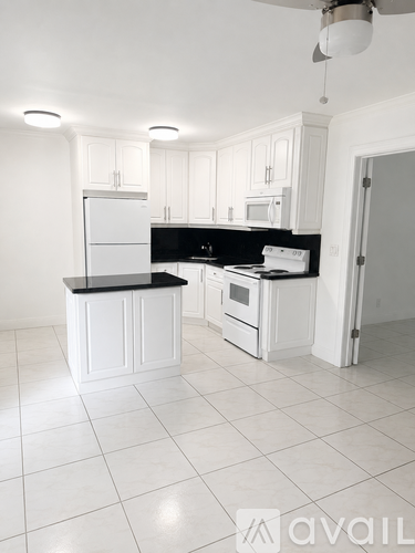 A kitchen with white cabinets and black countertops.