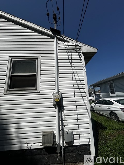 A utility pole with a yellow box and wires attached to a house.