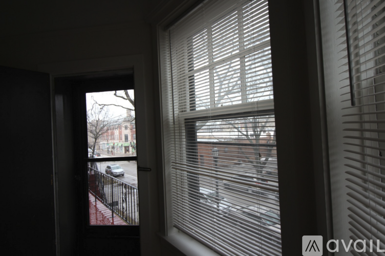 A view of a street through a window with blinds.