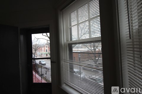 A view of a street through a window with blinds.
