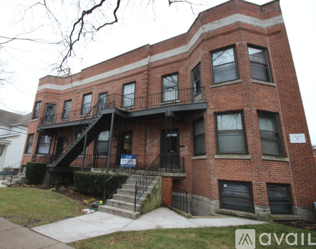 A red brick building with a balcony and a sign that says "available".
