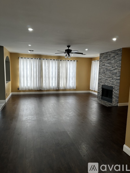 A spacious room with a fireplace and a ceiling fan.