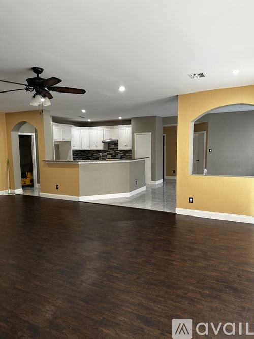 A spacious room with a ceiling fan and wooden flooring.