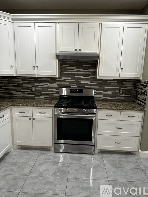 A kitchen with a stove top oven and cabinets.