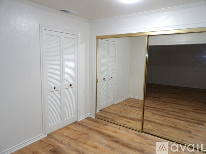 A room with a wooden floor and a large mirror on the wall.