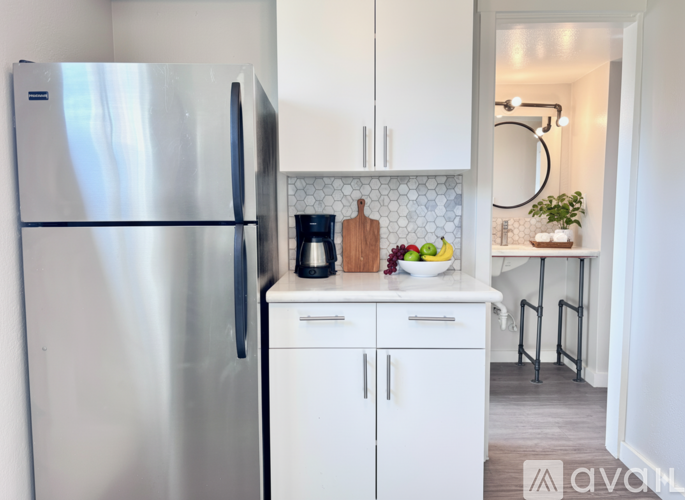 A kitchen with a stainless steel refrigerator and white cabinets.