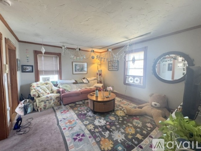 A living room with a couch, a chair, a coffee table, a teddy bear, and a rug.