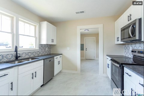 A kitchen with white cabinets and black countertops.