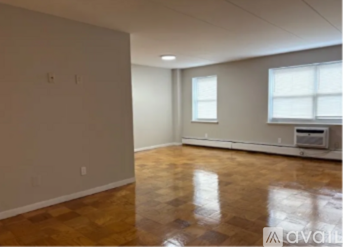A spacious room with wooden flooring and a window.