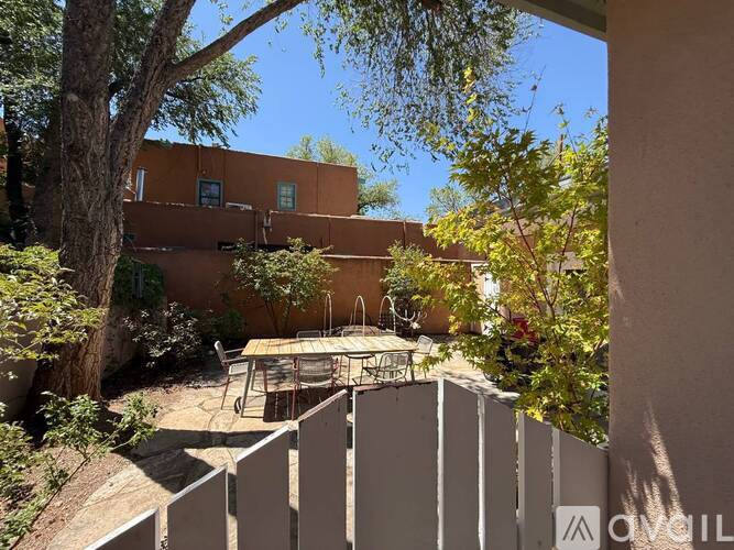 A patio with a table and chairs is surrounded by a fence and trees.